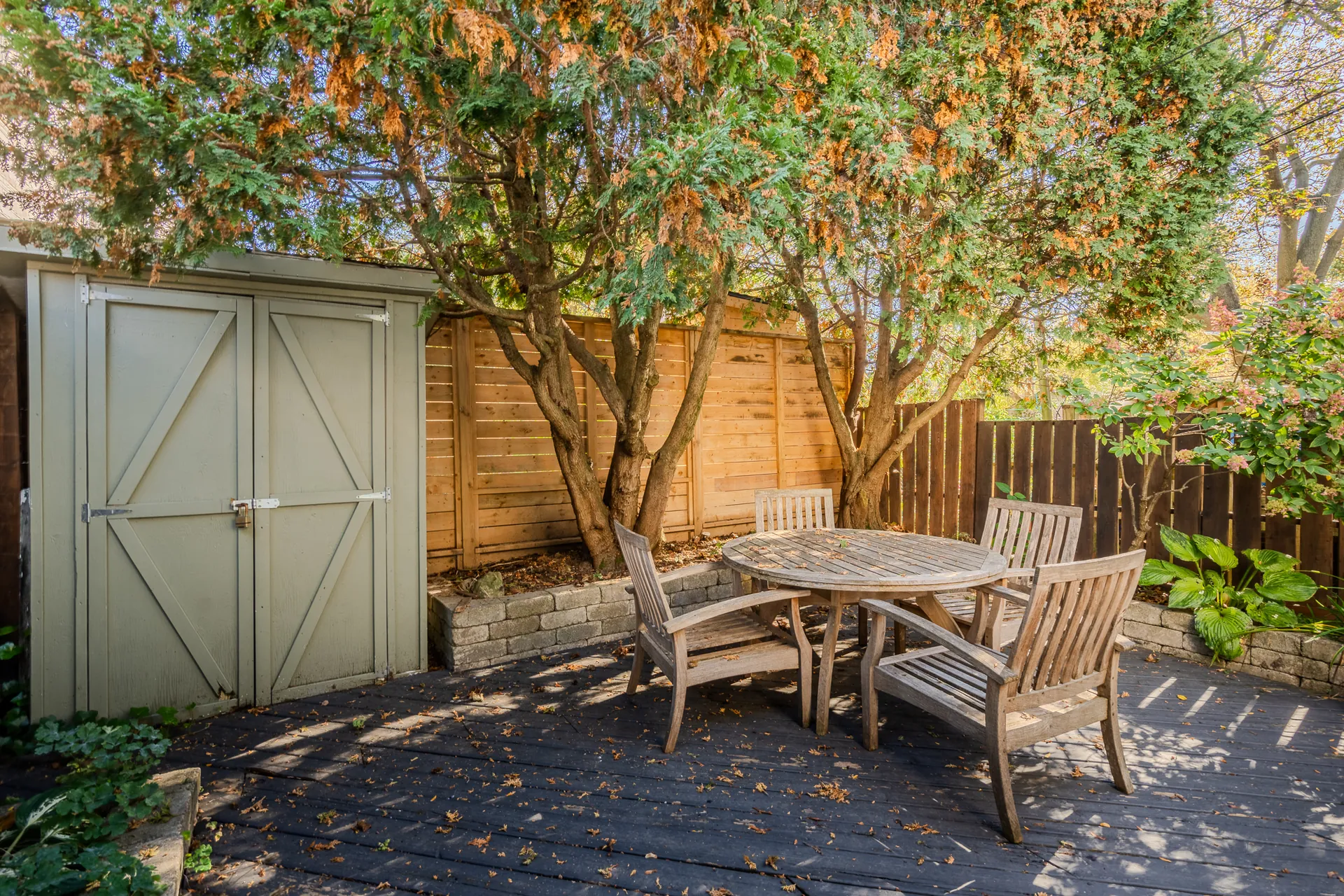 Private fenced deck with patio table, surrounded by mature trees