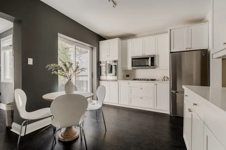 Eat-in kitchen with white cabinetry, stainless steel appliances and a breakfast table